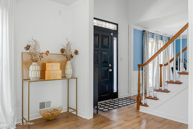 entrance foyer featuring a wealth of natural light, wood-type flooring, visible vents, and stairs