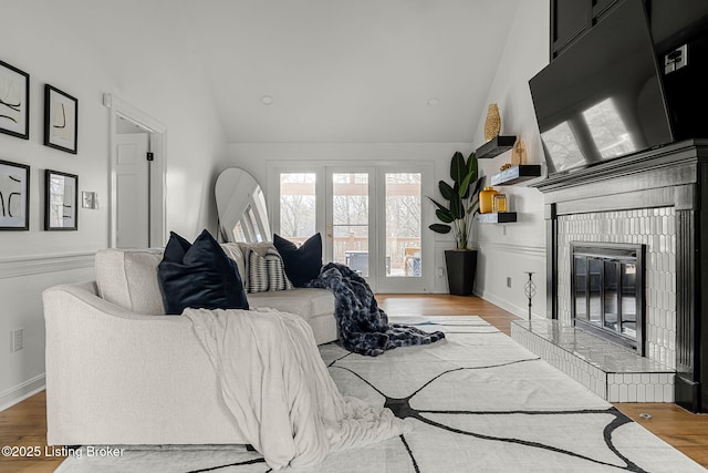 living area featuring high vaulted ceiling, a fireplace, and wood finished floors