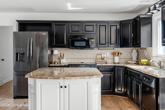 kitchen featuring light wood finished floors, black appliances, dark cabinetry, and decorative backsplash