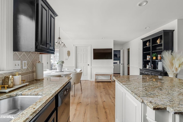 kitchen with light wood-type flooring, tasteful backsplash, dark cabinetry, and dishwasher