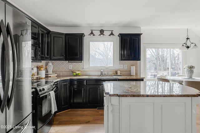 kitchen featuring black appliances, dark cabinetry, and a sink