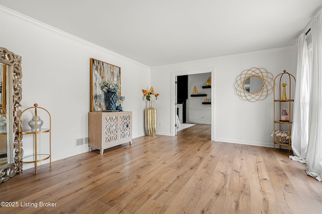 empty room with ornamental molding, visible vents, baseboards, and wood finished floors