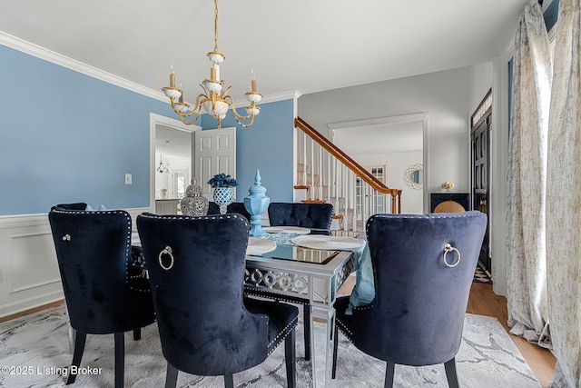 dining area featuring crown molding, wainscoting, wood finished floors, and a notable chandelier