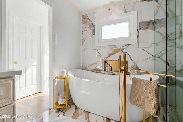 bathroom featuring a freestanding tub, ornamental molding, and marble finish floor