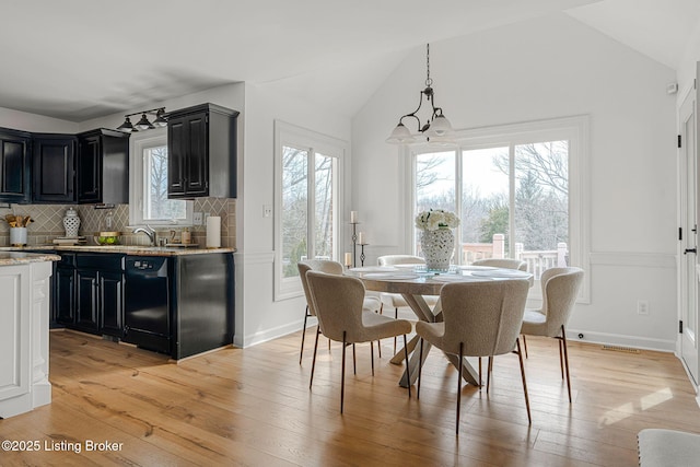 dining area featuring lofted ceiling, plenty of natural light, and light wood-style floors