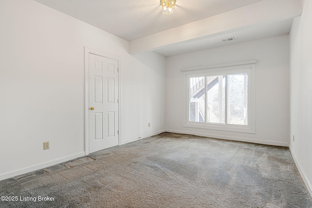 empty room featuring carpet floors, visible vents, and baseboards