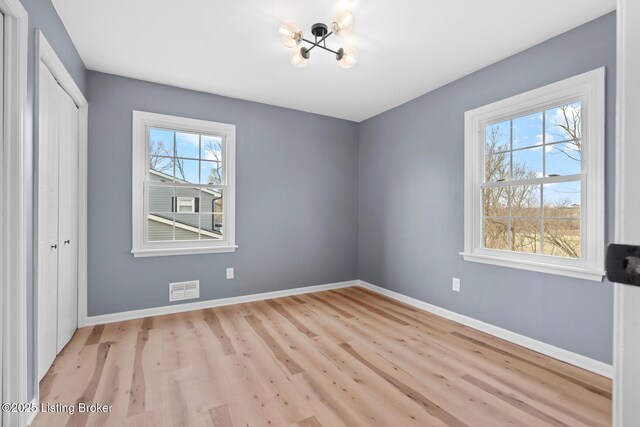 unfurnished bedroom with a closet, visible vents, baseboards, and wood finished floors