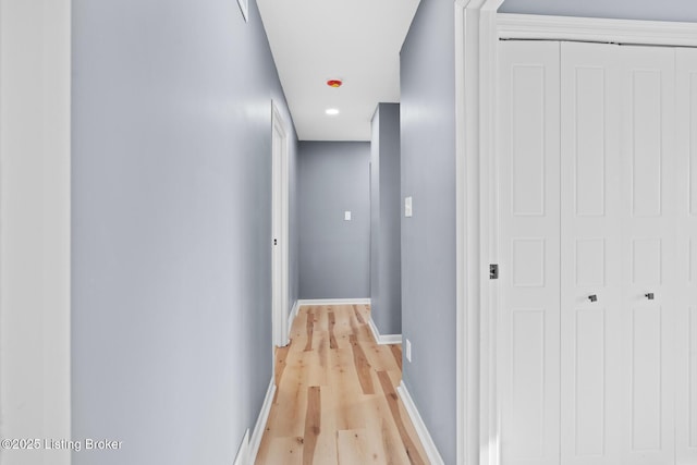 corridor featuring light wood-type flooring and baseboards