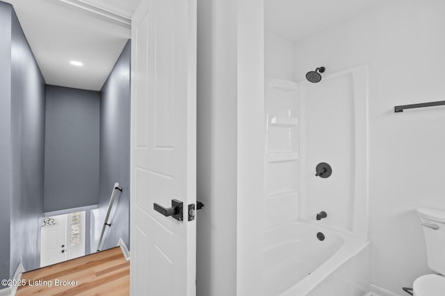 bathroom featuring shower / washtub combination, wood finished floors, and toilet