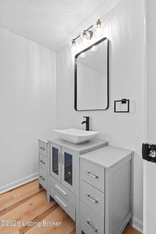 bathroom with wood finished floors, vanity, and baseboards