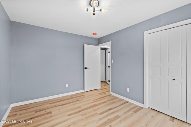 unfurnished bedroom with a closet, wood finished floors, and baseboards