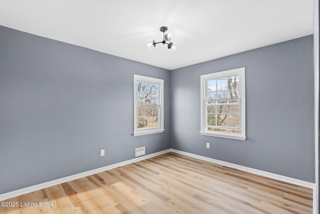 spare room with visible vents, baseboards, and wood finished floors