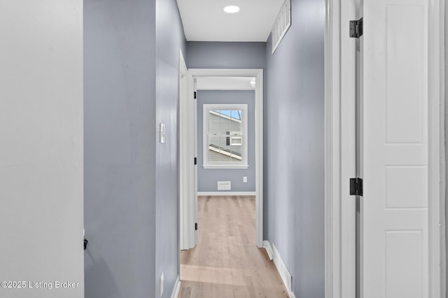 corridor featuring light wood finished floors, visible vents, and baseboards