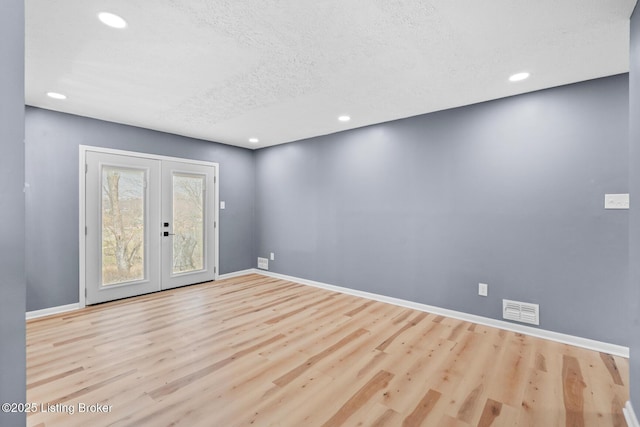 unfurnished room with baseboards, visible vents, wood finished floors, and french doors