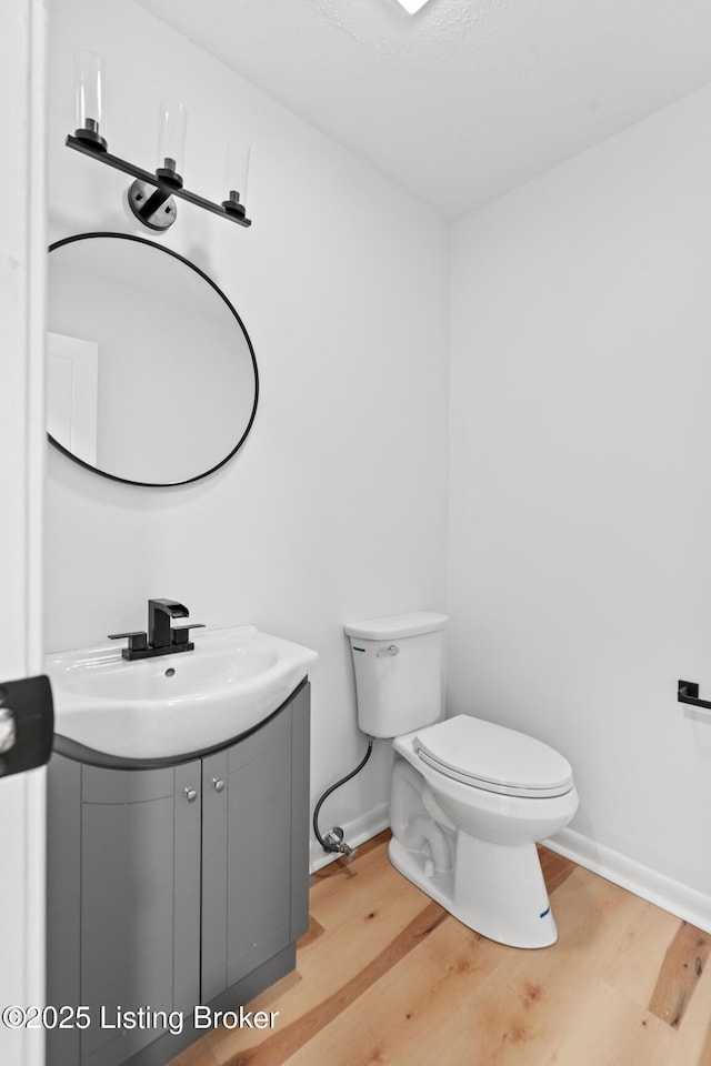 bathroom with vanity, wood finished floors, toilet, and baseboards