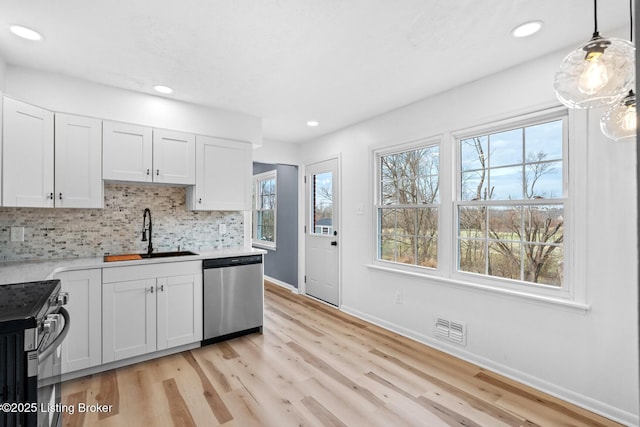 kitchen featuring a sink, visible vents, light countertops, appliances with stainless steel finishes, and backsplash