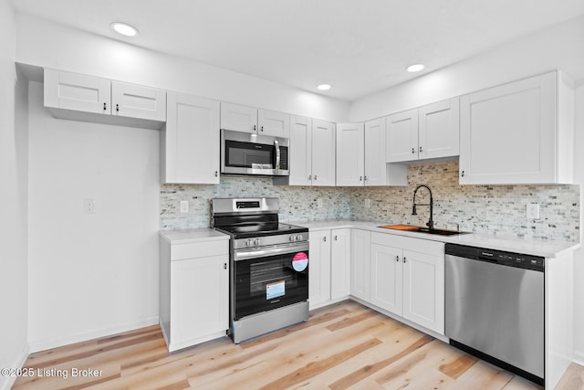 kitchen with stainless steel appliances, light countertops, a sink, and light wood-style flooring