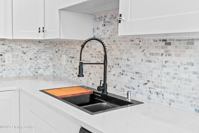 kitchen featuring white cabinets, light countertops, a sink, and backsplash