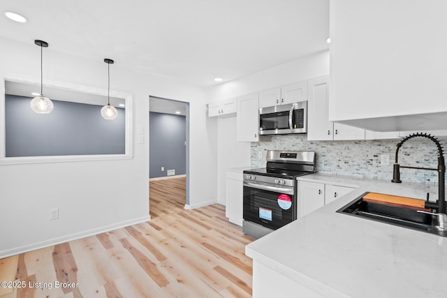 kitchen featuring a sink, white cabinets, light countertops, appliances with stainless steel finishes, and tasteful backsplash