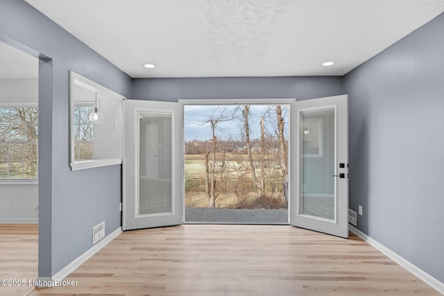 entryway featuring a textured ceiling, wood finished floors, visible vents, and baseboards