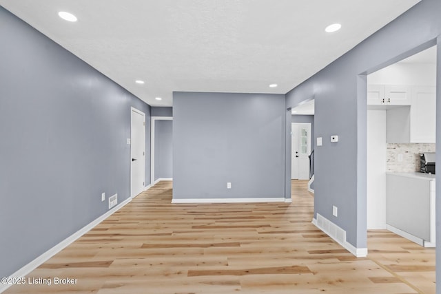 empty room featuring baseboards, recessed lighting, and light wood-style floors