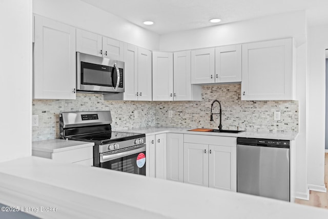 kitchen with appliances with stainless steel finishes, light countertops, a sink, and white cabinetry