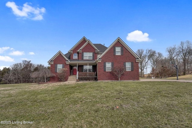 view of front facade with brick siding, covered porch, and a front lawn