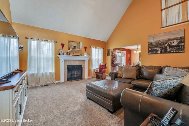 living area with a tiled fireplace, plenty of natural light, high vaulted ceiling, and carpet