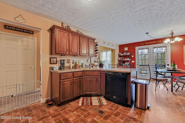 kitchen featuring visible vents, a sink, a peninsula, brown cabinetry, and dishwasher