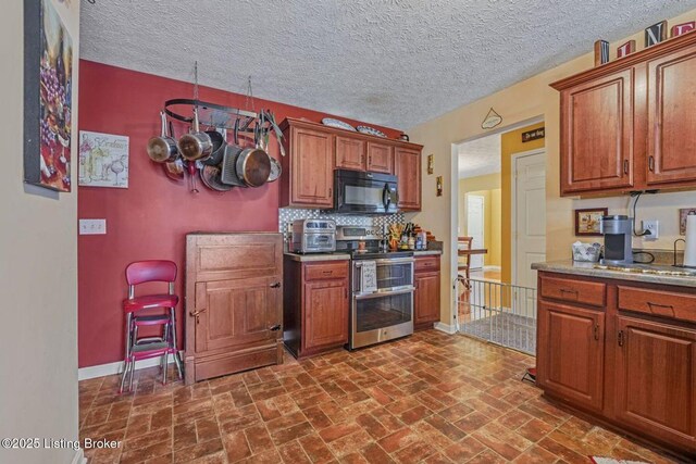 kitchen with double oven range, baseboards, brown cabinets, black microwave, and tasteful backsplash