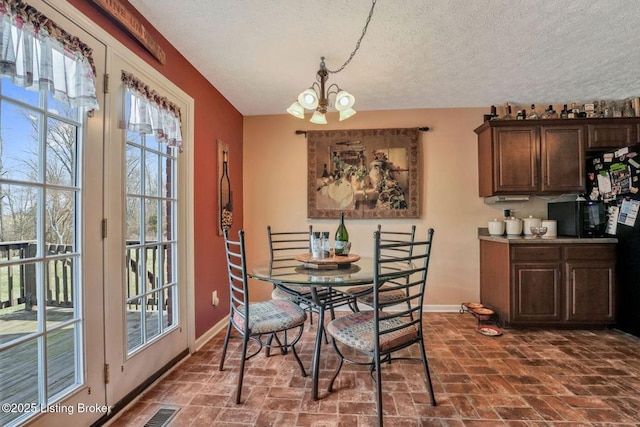 dining area featuring an inviting chandelier, brick floor, visible vents, and baseboards