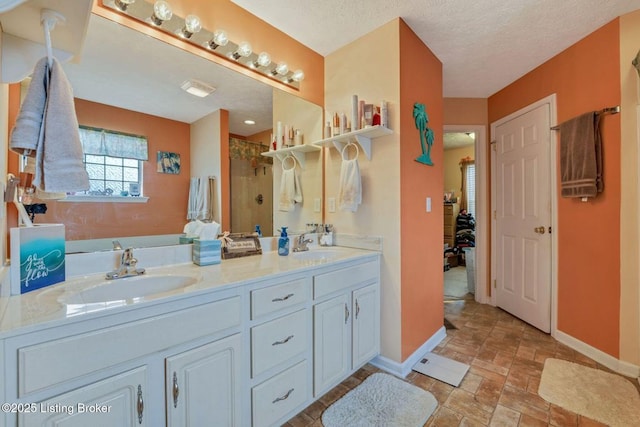 bathroom featuring a shower stall, stone finish flooring, baseboards, and a sink