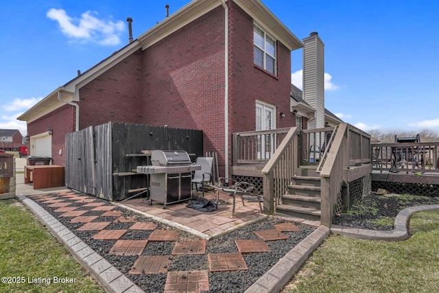 rear view of property with a wooden deck, a patio, brick siding, and fence