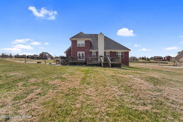 back of property with a wooden deck, a chimney, and a yard