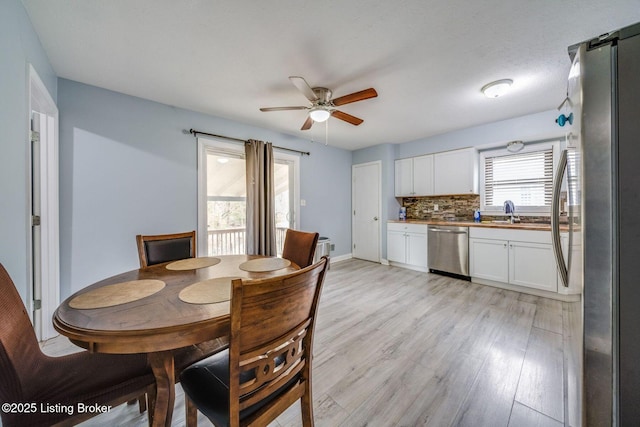 dining area with light wood-style flooring, baseboards, and a ceiling fan