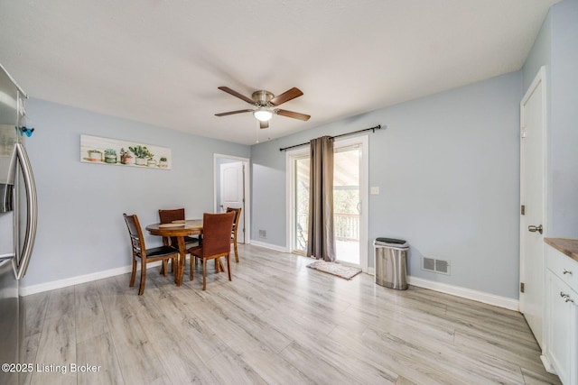 dining room featuring a ceiling fan, light wood-type flooring, visible vents, and baseboards