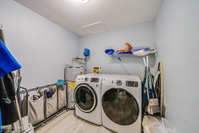 washroom with laundry area, attic access, washer and clothes dryer, wood finished floors, and water heater