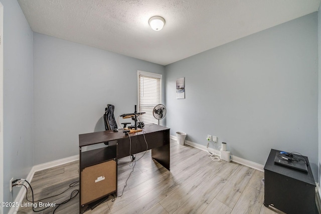 home office with baseboards, a textured ceiling, and light wood finished floors