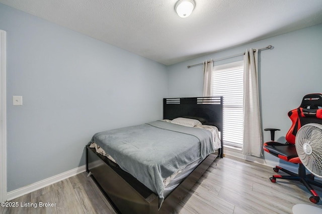 bedroom featuring a textured ceiling, wood finished floors, and baseboards