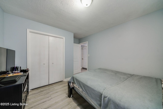 bedroom featuring a textured ceiling, light wood finished floors, and a closet