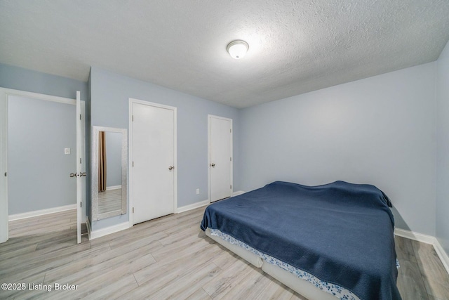 bedroom featuring a textured ceiling, wood finished floors, and baseboards