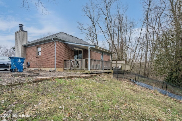 rear view of property with brick siding, a chimney, and a wooden deck