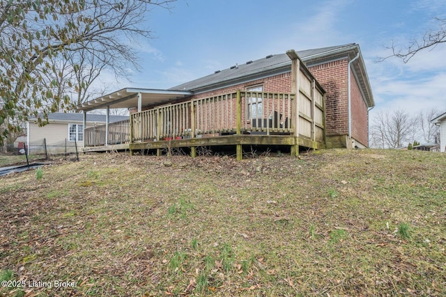 rear view of house featuring a deck, a carport, and brick siding