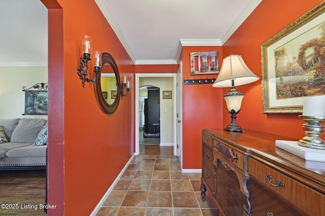 hallway with arched walkways, dark tile patterned floors, baseboards, and crown molding