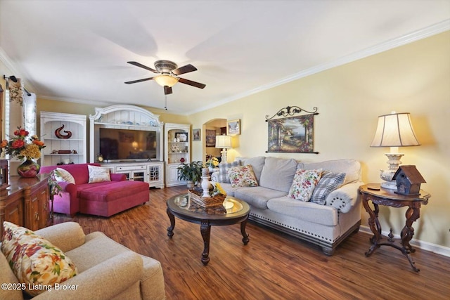 living area with arched walkways, wood finished floors, a ceiling fan, baseboards, and ornamental molding