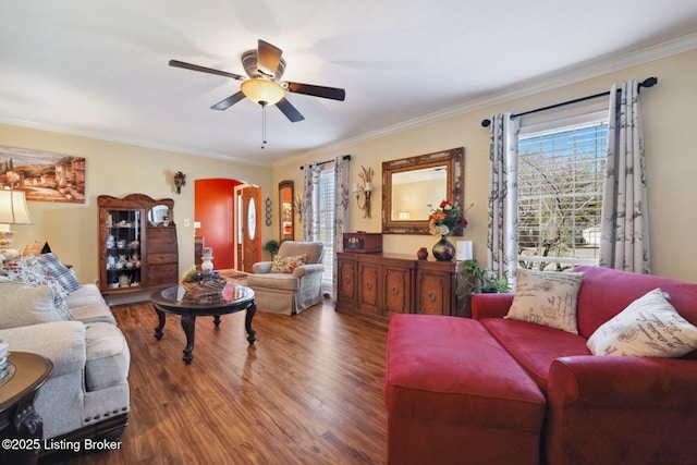 living room featuring ceiling fan, arched walkways, wood finished floors, and ornamental molding