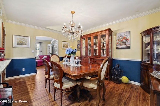 dining space with arched walkways, dark wood-type flooring, ornamental molding, and baseboards