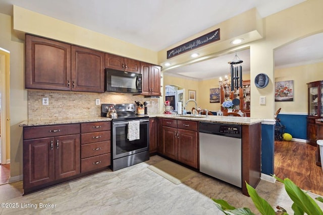 kitchen featuring a peninsula, tasteful backsplash, appliances with stainless steel finishes, and a sink