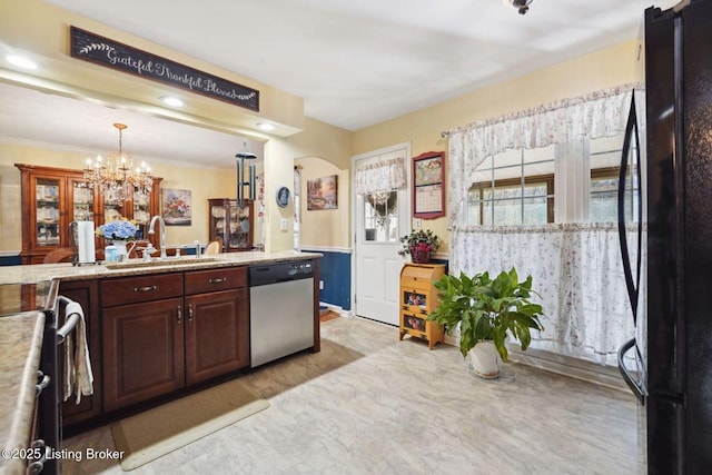 kitchen featuring pendant lighting, stainless steel dishwasher, ornamental molding, freestanding refrigerator, and a sink