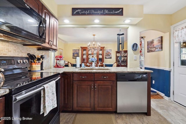 kitchen with a peninsula, a sink, ornamental molding, appliances with stainless steel finishes, and decorative backsplash